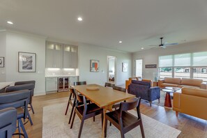 Amplia sala de estar con una mesa de comedor, sillas, un sofá y una cocina al fondo.