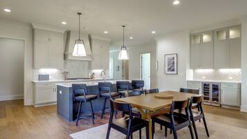 A modern kitchen with a central island, bar stools, and pendant lighting.