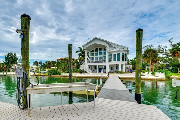 A waterfront property with a dock, a modern house with large windows, and a clear sky.