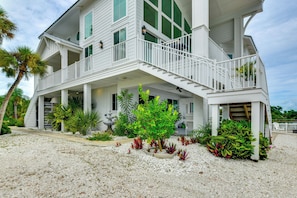 A two-story house with a balcony, a covered porch, and a garden with various plants.