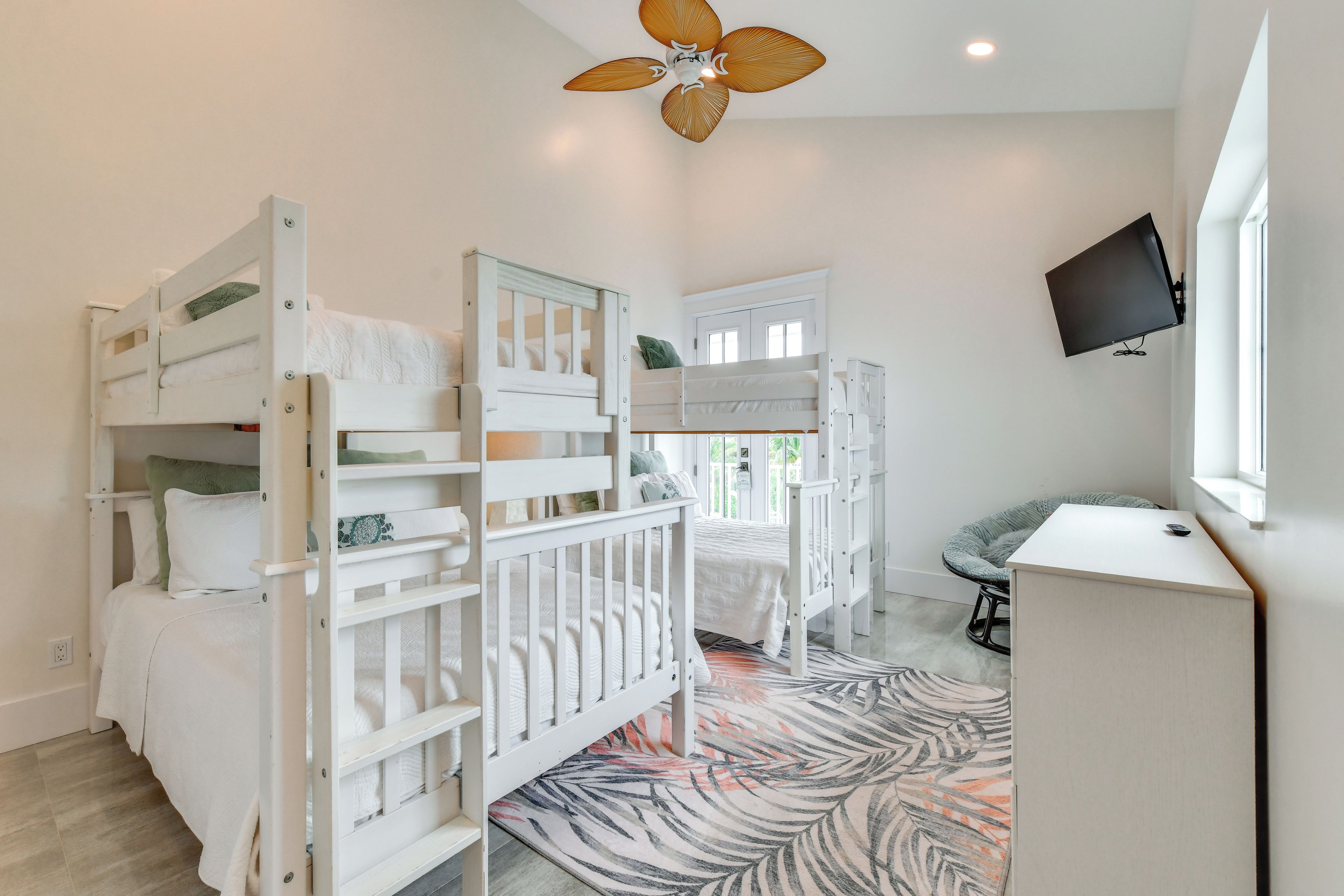 A children's room with bunk beds, a desk, and a television.