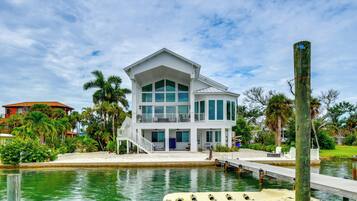 A two-story waterfront property with a dock and a boat.