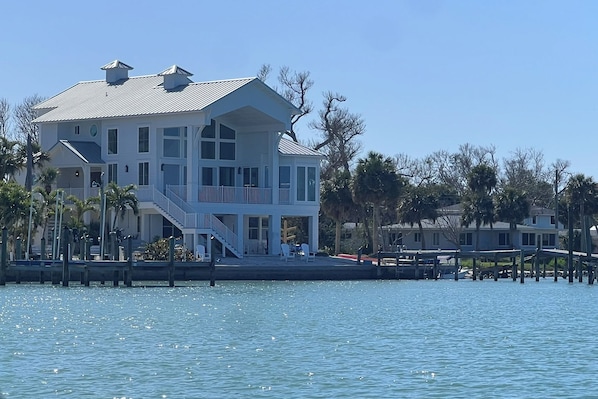 A waterfront property with a large house featuring multiple balconies, a dock, and a clear view of the water. - Luxury Bayfront Home, Private Dock, Steps to Beach (Englewood)