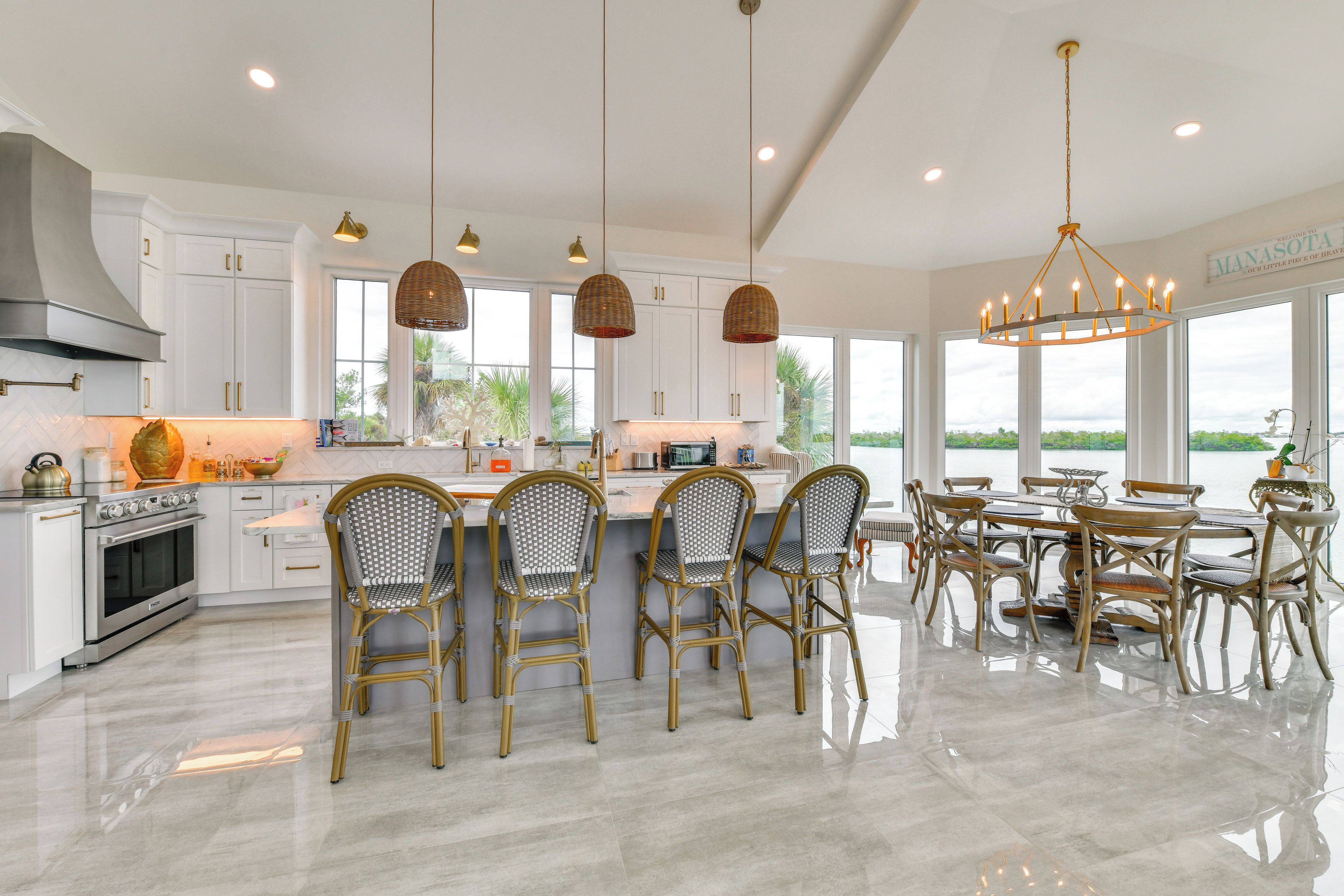 A modern kitchen with white cabinetry, a central island with bar stools, and a dining area with a large table and chairs.