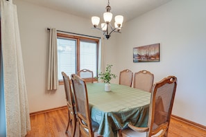 A dining room with a table set for four, surrounded by wooden chairs with woven backs.