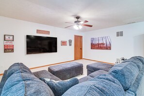 Un cinema en casa amb un televisor de pantalla plana, un ventilador de sostre i un pòster de pel·lícula a la paret.