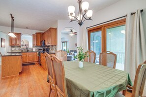 A spacious kitchen with wooden cabinets, a dining area with a table and chairs, and a large window with blinds.
