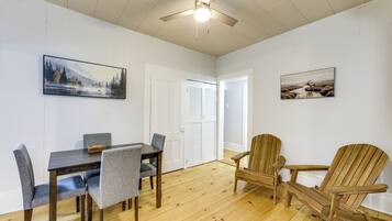 A dining area with a table and chairs, a ceiling fan, and two framed pictures on the walls.