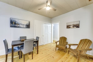 A dining area with a table and chairs, a ceiling fan, and two framed pictures on the walls.