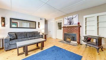 A living room with a sofa, coffee table, fireplace, and a blue rug.