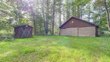 A rustic wooden cabin with a sloped roof and a smaller shed with a cross-braced door.