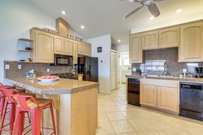 Una cocina con armarios de madera, encimera de granito, refrigerador, lavavajillas y ventilador de techo.