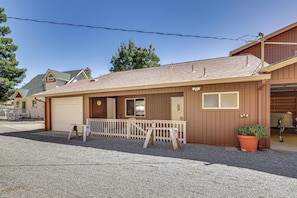 A two-story building with a covered porch, a garage, and a small outdoor seating area. - Panoramic Views! Clear Lake Cottage w/ Patio (Clearlake)