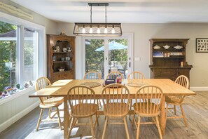 A dining room with a large wooden table, six chairs, and a chandelier.