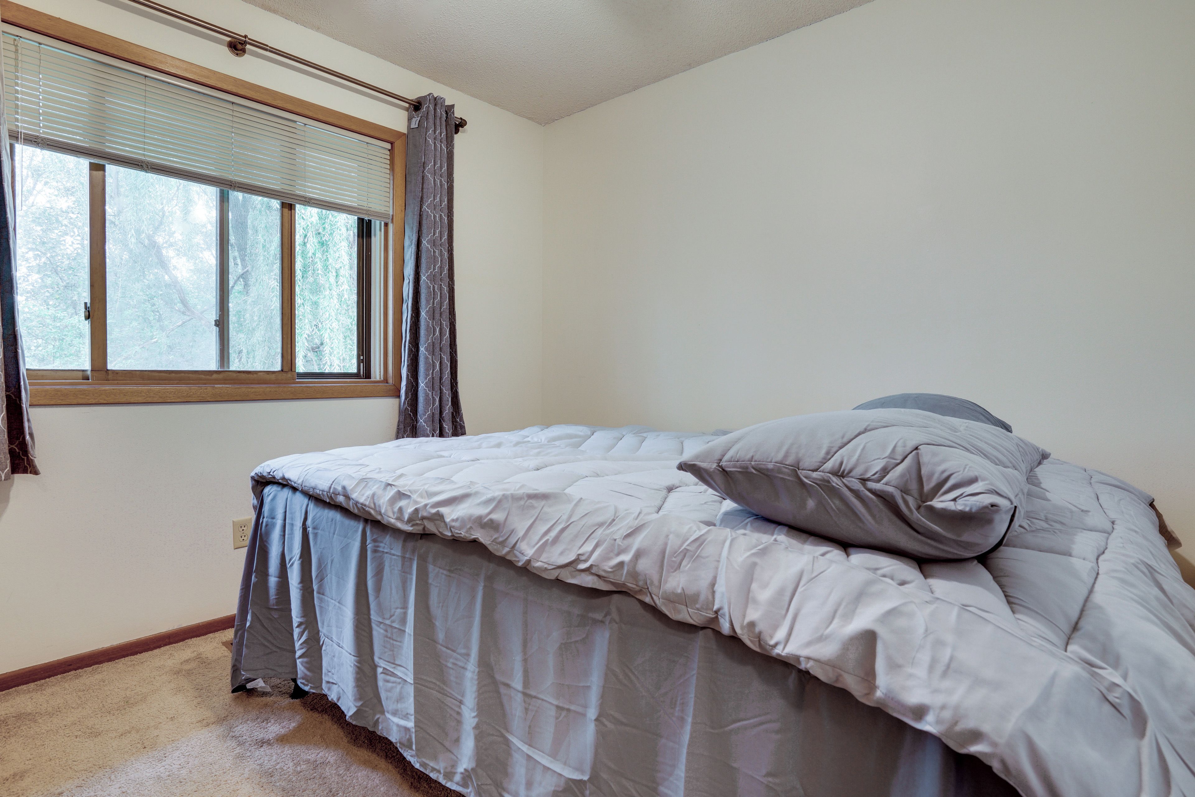 Un dormitorio con una cama, una ventana con persianas y una cortina.