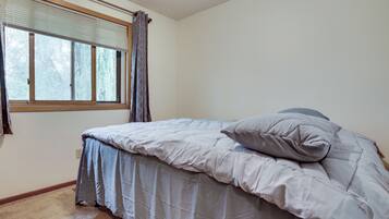 Un dormitorio con una cama, una ventana con persianas y una cortina.