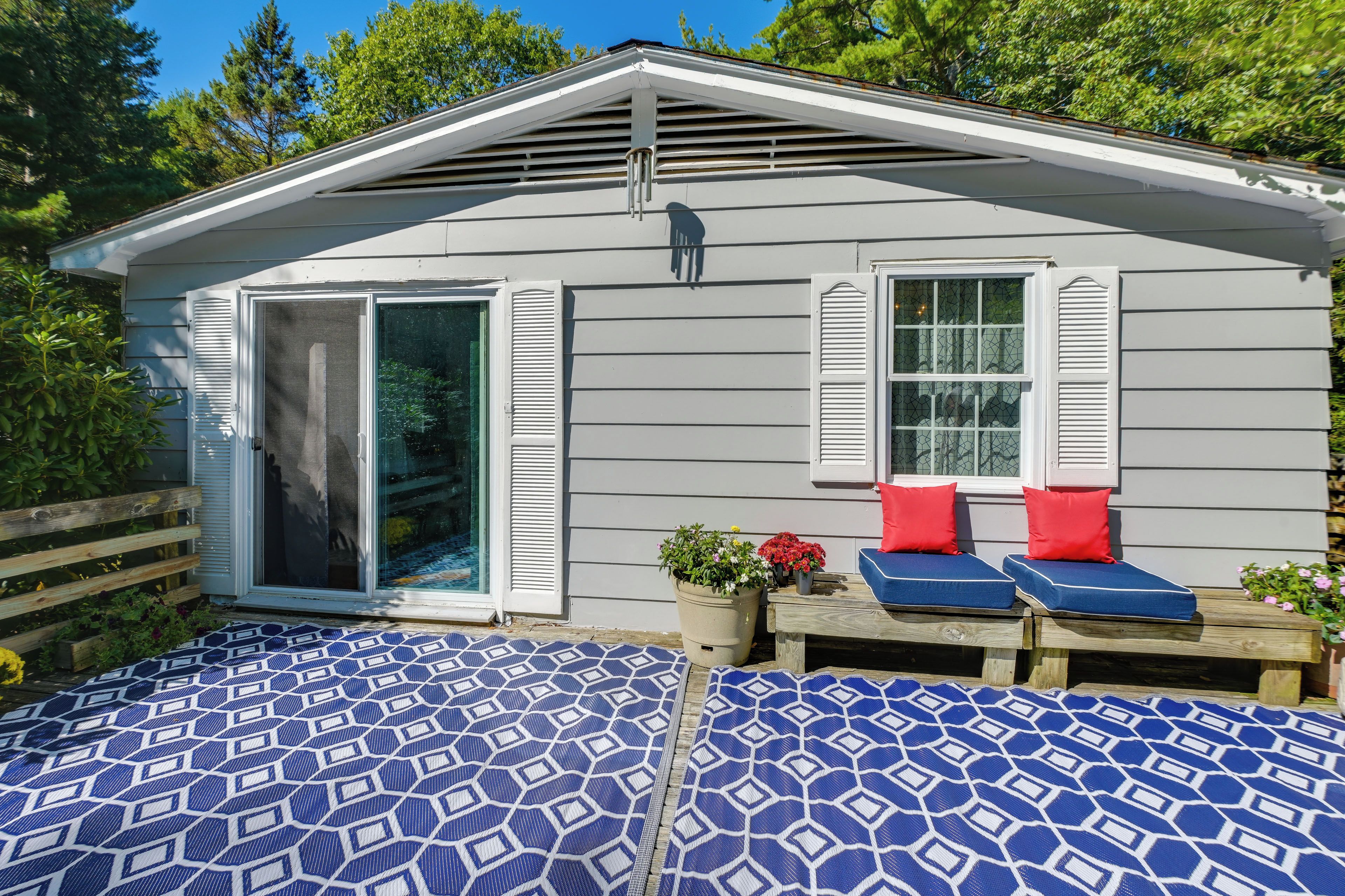 A small house with a covered patio area featuring two blue patterned outdoor beds.