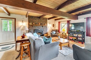 A cozy living room with a fireplace, comfortable seating, and a bookshelf. - White Mtn Views & Game Room in Edelweiss Village (Madison)