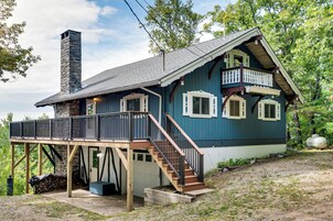 Una casa de dos pisos con balcón, chimenea y garaje.