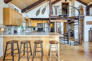 Una cocina amplia con electrodomésticos modernos, una isla grande con taburetes y una escalera en espiral.