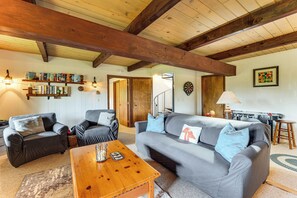 A cozy living room with a sofa, armchairs, a wooden coffee table, and a dartboard. - White Mtn Views & Game Room in Edelweiss Village (Madison)