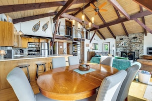 Una cocina amplia con electrodomésticos modernos, un comedor con mesa de madera y una chimenea de piedra en la sala de estar.