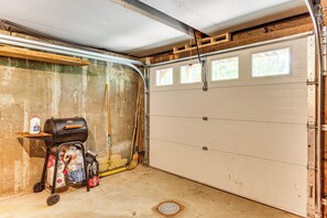 A garage with a concrete floor, a wooden workbench, a barbecue grill, and cleaning supplies. - White Mtn Views & Game Room in Edelweiss Village (Madison)