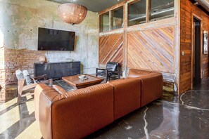 A modern living room with a leather sofa, a coffee table, and a flat-screen TV mounted on the wall. - Historic Loft of Comer! Walk to Shops & Dining (Comer)