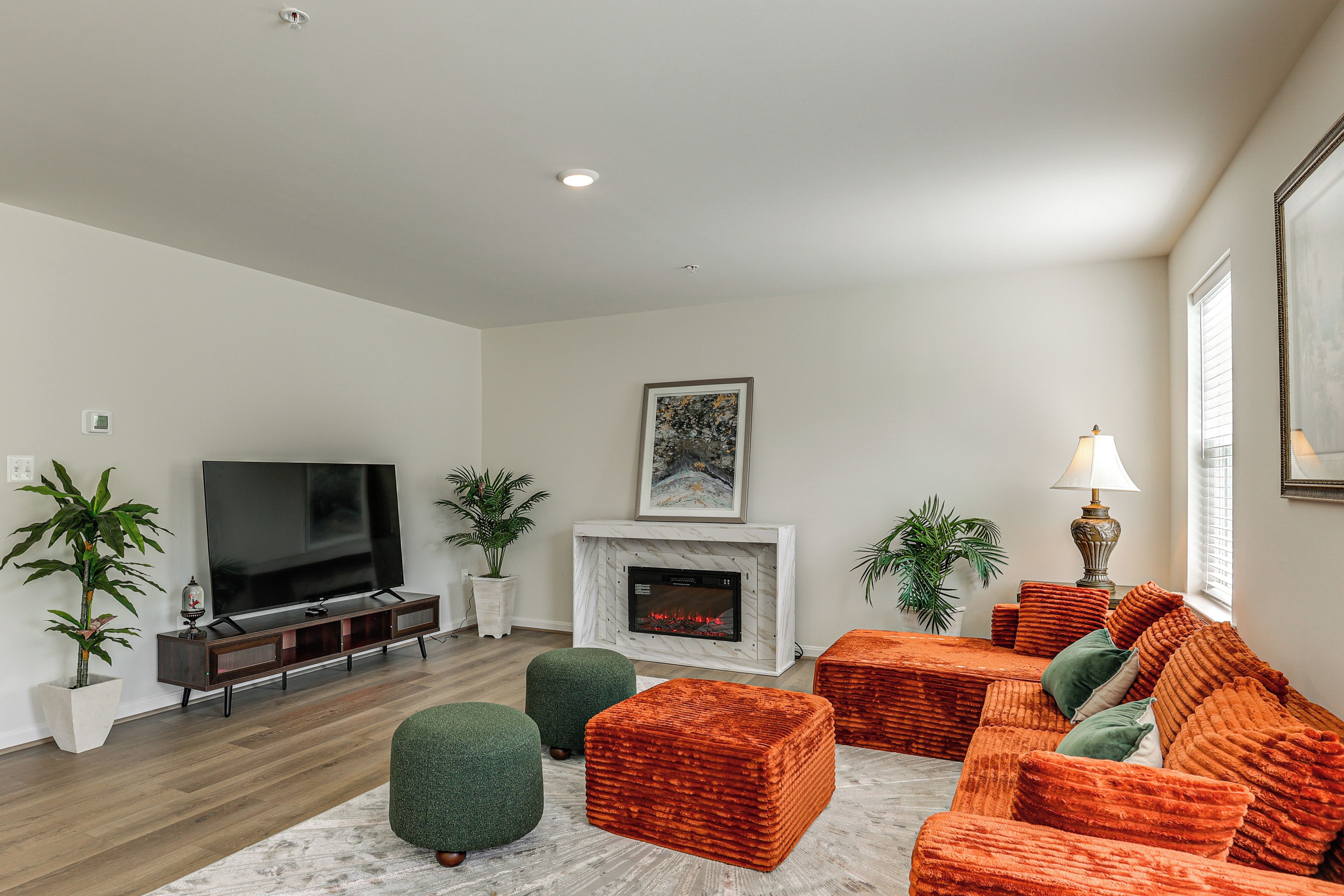 A modern living room with a flat-screen TV, a fireplace, and a sofa set.