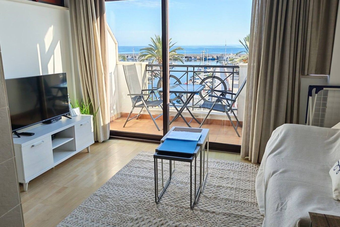 Ein Hotelzimmer mit Balkon, Fernseher, kleinem Tisch und Bett.