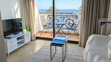 Ein Hotelzimmer mit Balkon, Fernseher, kleinem Tisch und Bett.