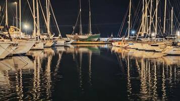 Ein Yachthafen bei Nacht mit vertäuten Booten und ruhigem Wasser, das die Lichter reflektiert.