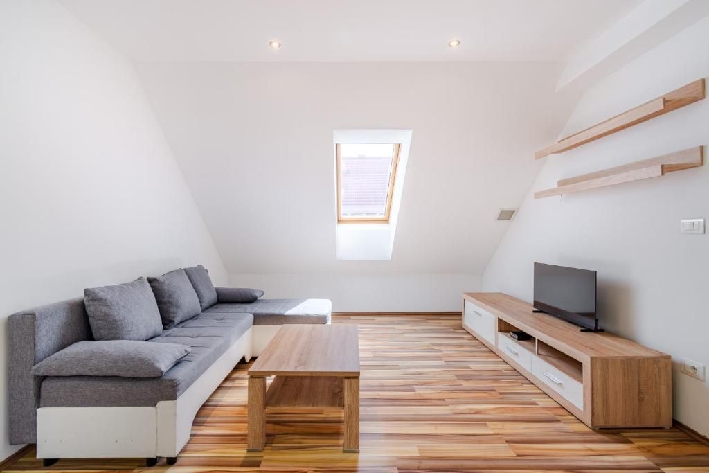 Un soggiorno moderno con un divano, un tavolino, una televisione su un mobile in legno e un lucernario.