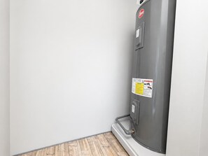 A corner of a room with a grey water heater against a white wall and wooden flooring. - Welcoming 2-bedroom Loft In Providencia For 5 (Providencia)