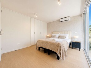 A bedroom with a bed, bedside tables, an air conditioning unit, and a large window. - Welcoming 2-bedroom Loft In Providencia For 5 (Providencia)