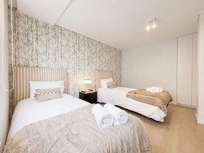 Een hotelkamer met twee bedden, een nachtkastje met een lamp en een kledingkast.