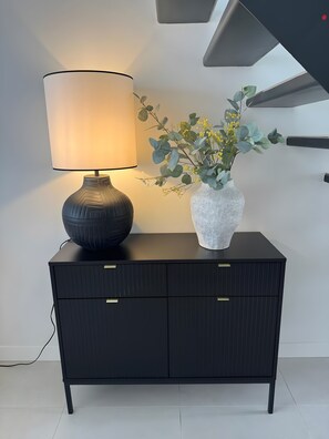 A black cabinet with two drawers and a lamp with a white shade on top.
