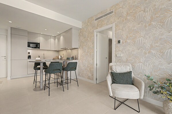 A modern kitchen with a dining area, a white door, and a patterned wallpaper.
