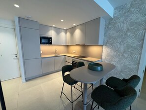 A modern kitchen with a built-in microwave, a sink, and a dining area with a round table and four chairs. - Apartment 'Duplex Bahía' with shared pool, private terrace and Wi-Fi (Málaga)