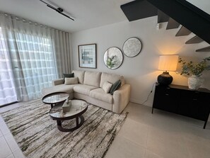 A modern living room with a sofa, a coffee table, and a lamp. - Apartment 'Duplex Bahía' with shared pool, private terrace and Wi-Fi (Málaga)