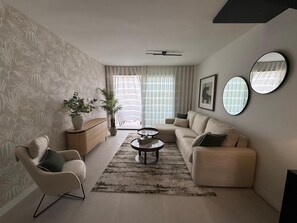 A modern living room with a sofa, armchair, coffee table, and decorative mirrors.
