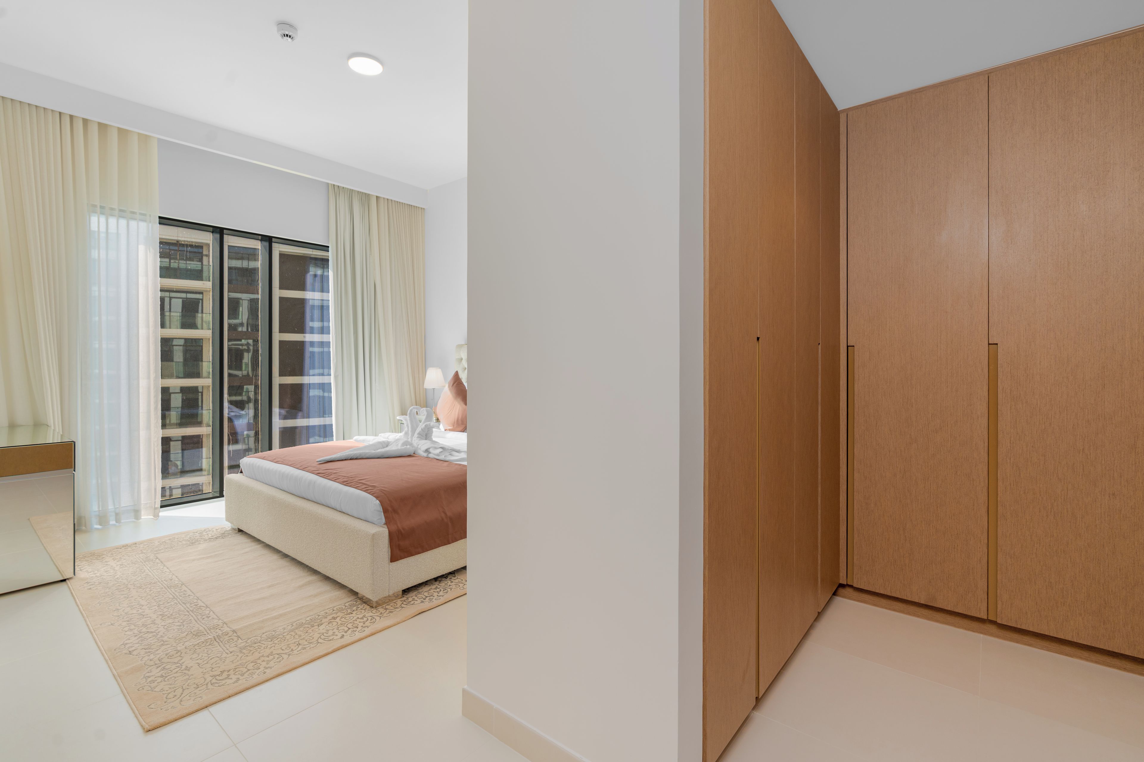 Een moderne slaapkamer met een bed, een groot raam en een houten garderobe.