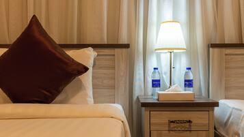 Habitación de hotel con una cama, una mesita de noche, una lámpara y dos botellas de agua.