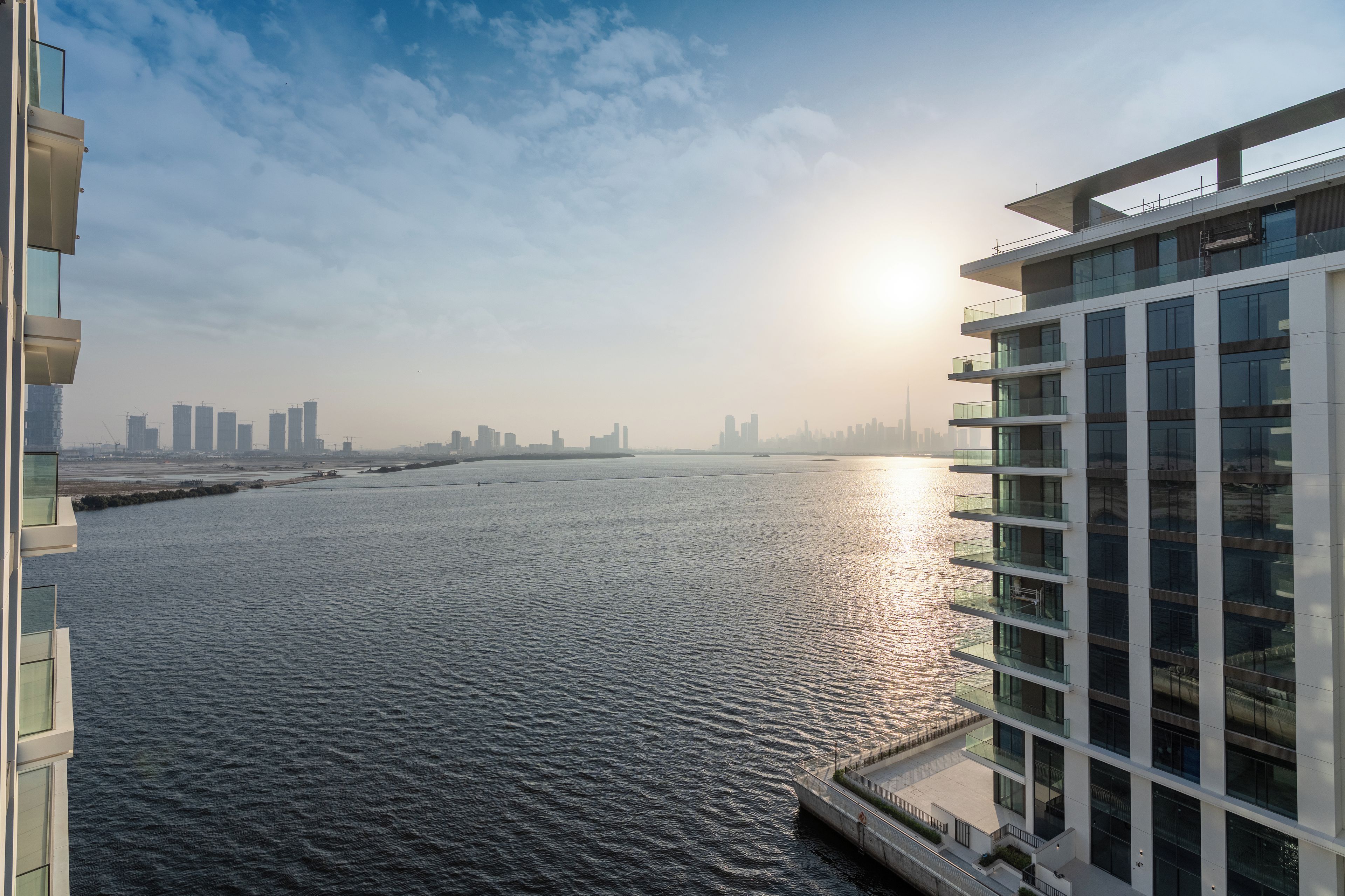 A high-rise building with a view of a river and a city skyline in the distance.