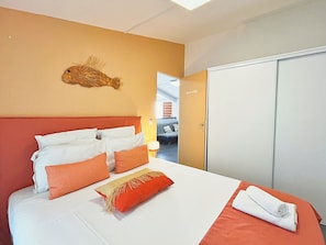 A hotel room with a bed, a door labeled 'RASCASSE,' and a wall-mounted fish decoration. - *VILLA KAP CORAIL* - pool and lagoon (Saint-Paul)