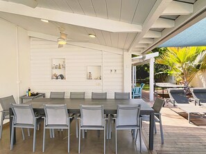 A covered outdoor dining area with a long table and chairs, a ceiling fan, and a view of the garden. - *VILLA KAP CORAIL* - pool and lagoon (Saint-Paul)