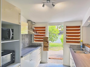 A compact kitchen with built-in appliances, a microwave, and a sink. - *VILLA KAP CORAIL* - pool and lagoon (Saint-Paul)