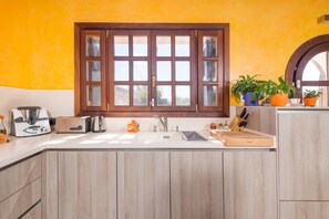 Eine Küche mit großem Fenster, Holzschränken und einer Spüle.