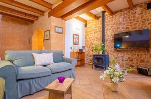 Ein gemütliches Wohnzimmer mit einer Couch, einem kleinen Holztisch, einem Kamin und einem an der Wand befestigten Fernseher.