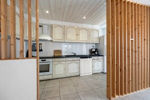 Cocina con armarios blancos, encimera negra y salpicadero de azulejos.
